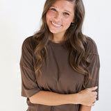 Smiling model with arm across her torso while wearing the Women's Short Sleeve Tee in Espresso