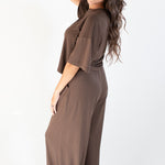 Model standing to the side with one hand in hair and wearing the Women's Wide Leg Pant in Espresso