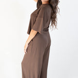Model standing to the side with one hand in hair and wearing the Women's Wide Leg Pant in Espresso