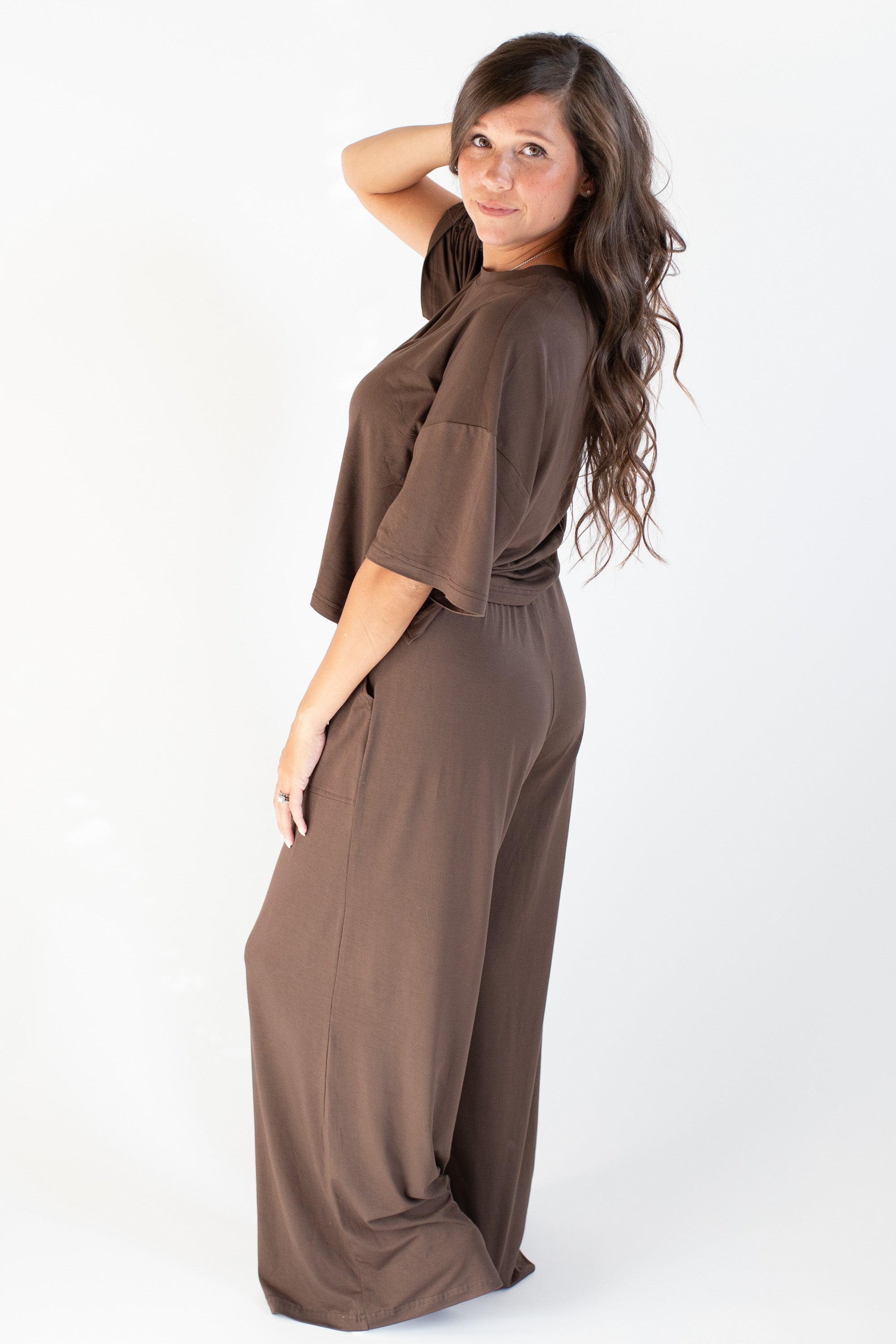 Model standing to the side with one hand in hair and wearing the Women's Wide Leg Pant in Espresso