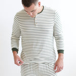 Male model holding the hem of the shirt of the Men's Ribbed Henley Set in Fir Stripe in front of a white background
