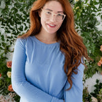 Close up of woman modeling periwinkle blue color jogger pajama set with greenery in background