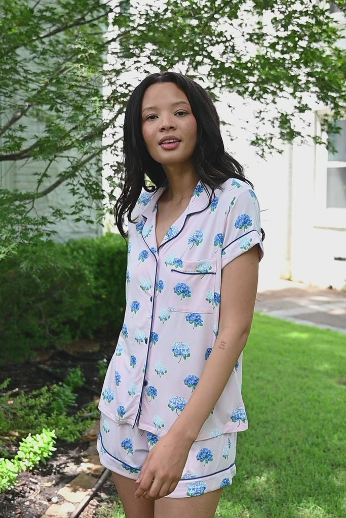 Woman outside looking over her shoulder in short sleeve and short pajamas in Hydrangea Sakura print. ::: Model is 5'10" wearing size S ///
