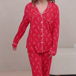 Video of a woman modeling candy cane printed red pajamas in a neutral room