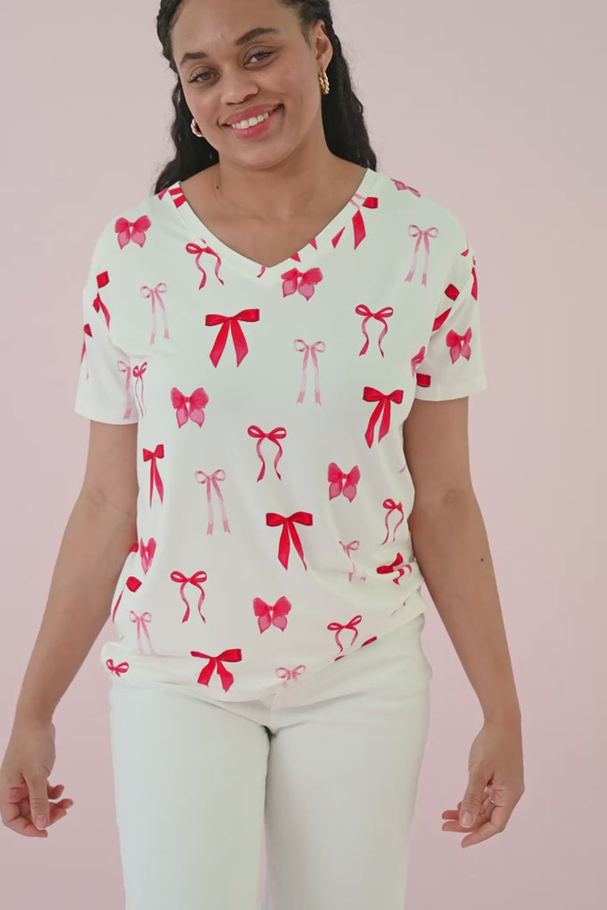 Woman modeling a relaxed fit v-neck tee white a red bow print