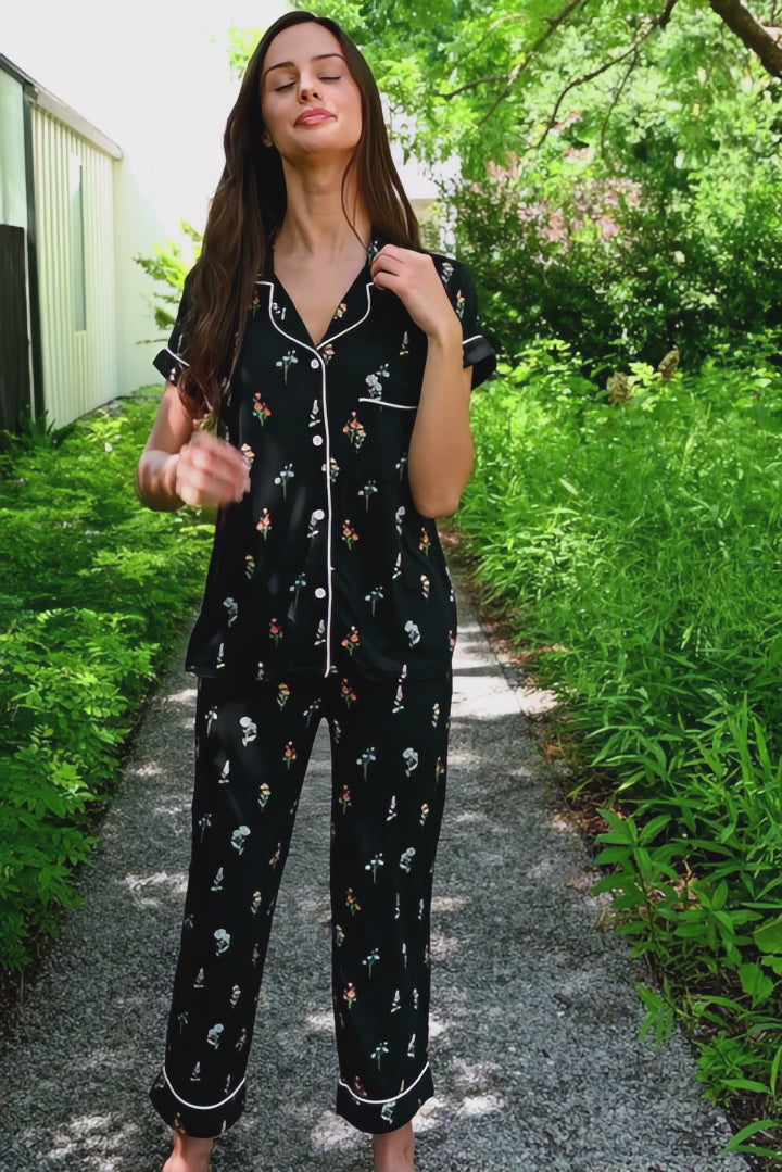 Woman modeling a black cropped pajama set with wildflower pattern in an outdoor setting 