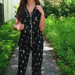 Woman modeling a black cropped pajama set with wildflower pattern in an outdoor setting ::: Model is 5'10" wearing size S ///