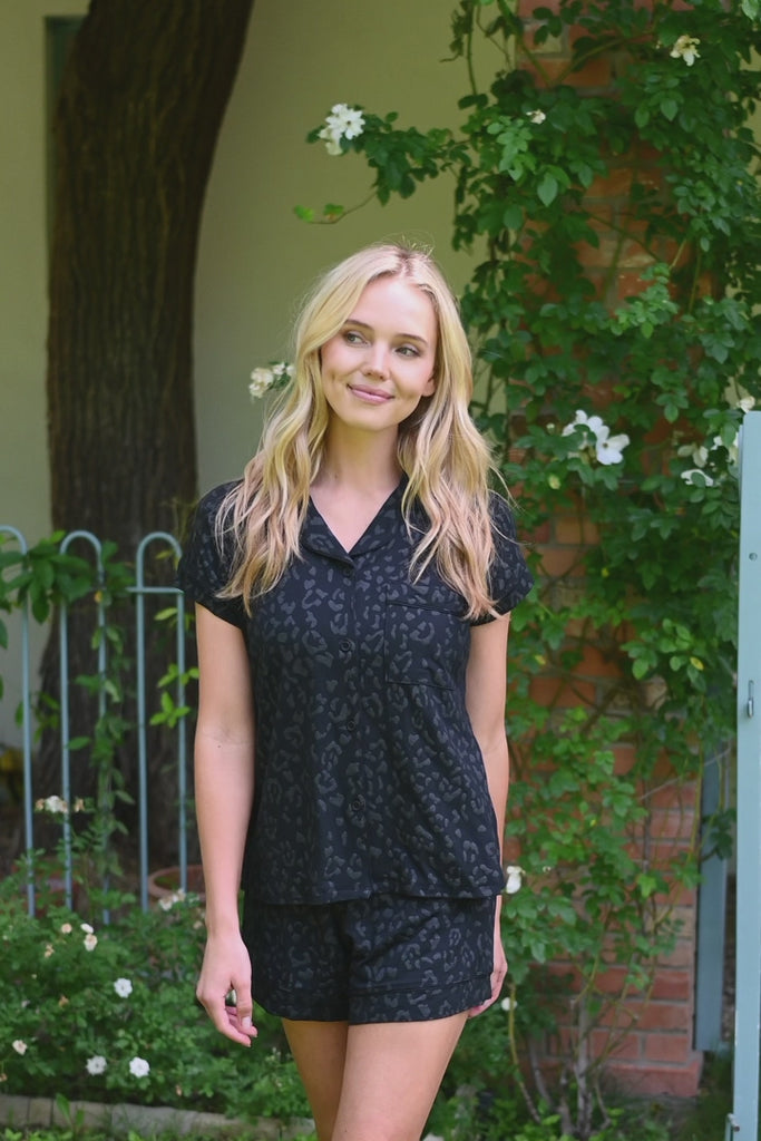 Video of woman modeling a short sleeve black pajama set with leopard print pattern outdoors  ::: Model is 5'9" wearing size XS ///