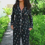 Woman modeling long sleeve black pajama set with wildflower pattern in outdoor setting ::: Model is 5'10" wearing size S ///
