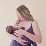 woman modeling nursing bra in currant while nursing baby