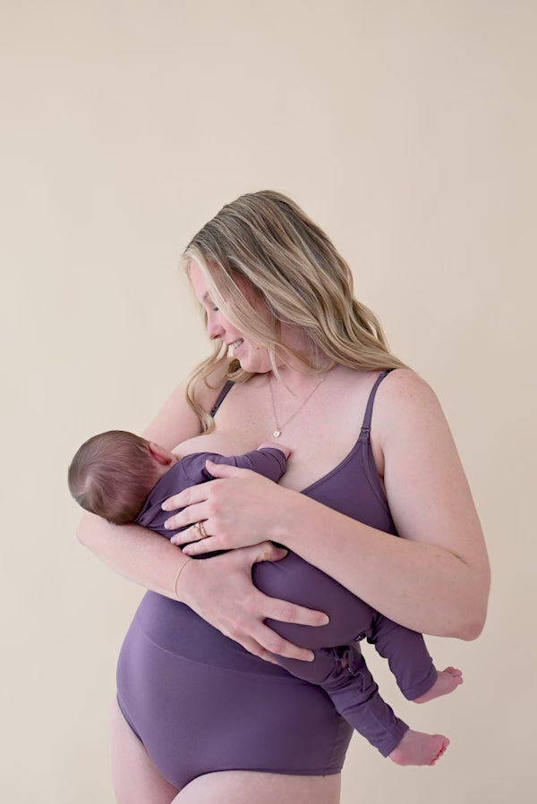 woman modeling nursing bra in currant while nursing baby