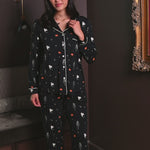 Woman modeling a black pajama set with halloween pattern including pumpkin, ghost and skeleton ::: Model is 5'9" wearing size S /// 