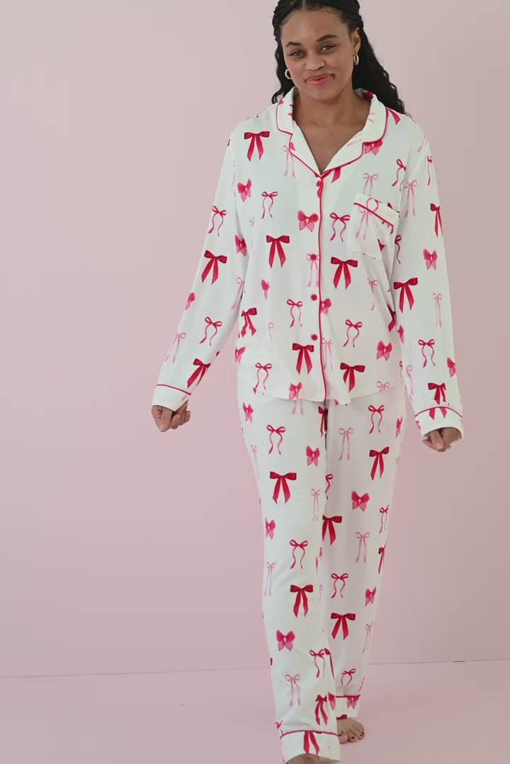 Woman modeling white pajama set with red buttons and a red bow pattern