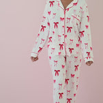 Woman modeling white pajama set with red buttons and a red bow pattern