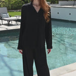Woman modeling black long sleeve pajamas by a pool  ::: Model is 5'6" wearing size S ///