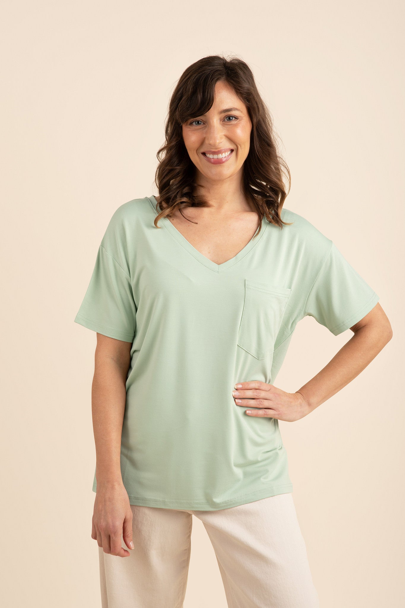 Smiling woman with hand on hip modeling the Bamboo Women's Relaxed Fit V-Neck in Basil ::: Model is 5'5" wearing size S ///