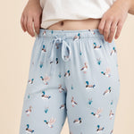 Light blue lounge pants with duck pattern worn by a person on a beige background