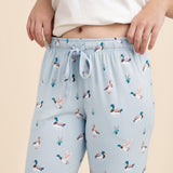 Light blue lounge pants with duck pattern worn by a person on a beige background