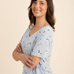 Woman wearing a light blue v-neck with a duck pattern on a beige background