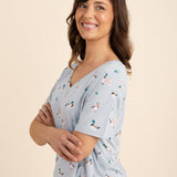 Woman wearing a light blue v-neck with a duck pattern on a beige background