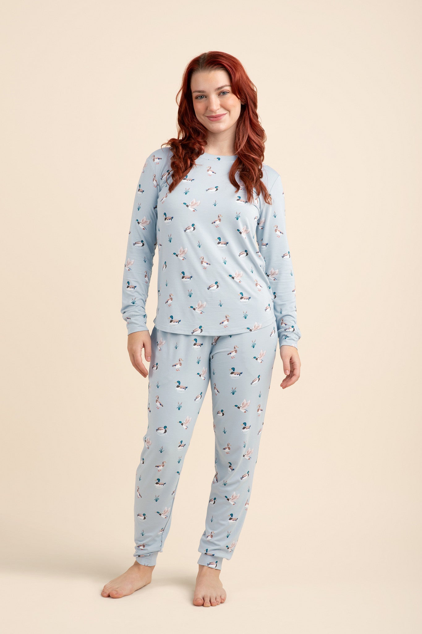 Woman wearing a light blue pajama set with a duck pattern on a beige background  