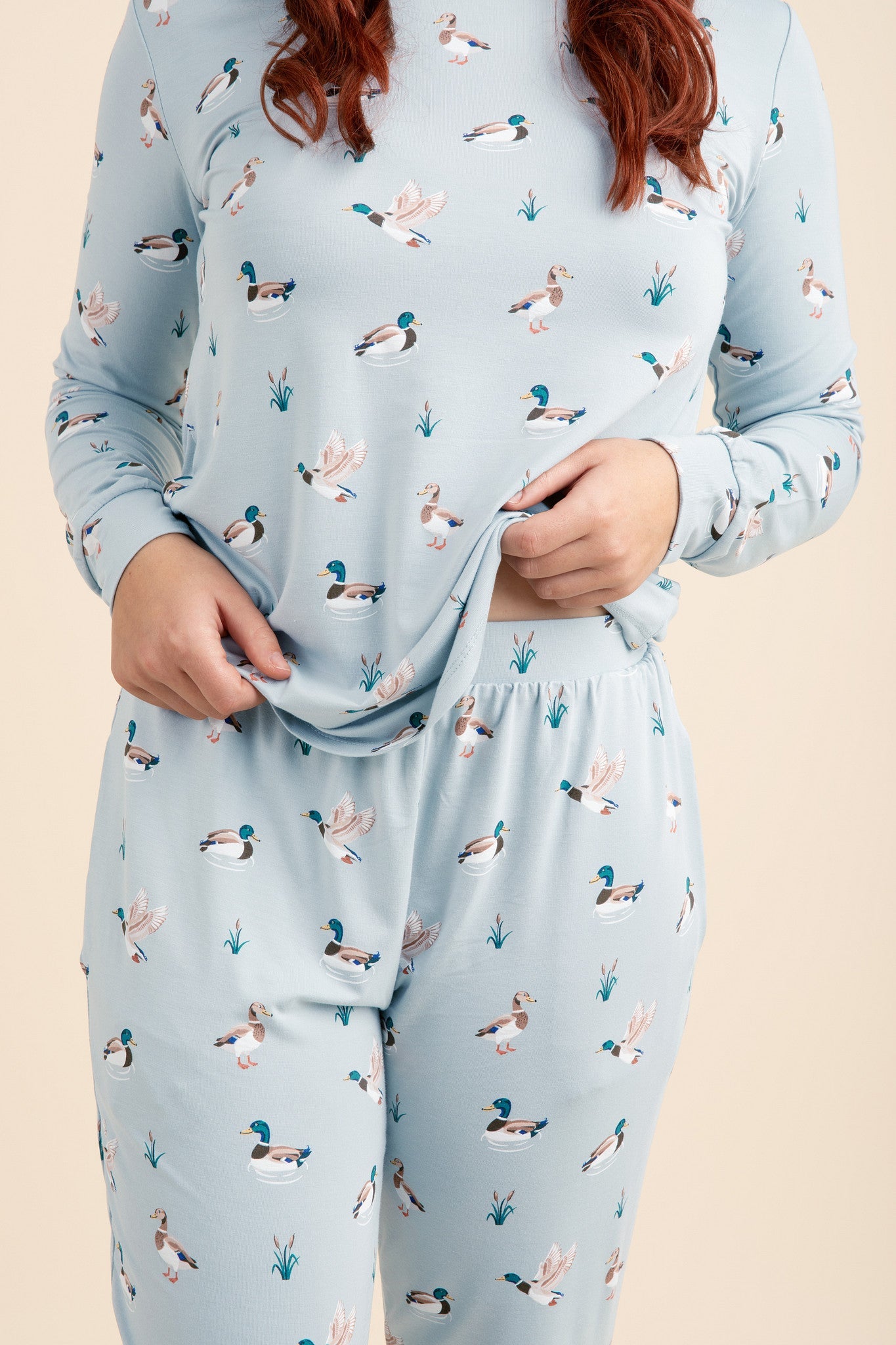 Light blue pajama set with duck pattern worn by a person on a beige background
