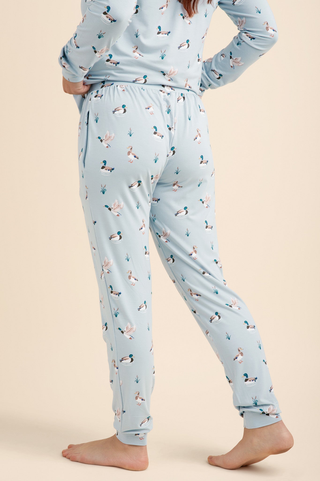 Light blue pajama set with duck pattern worn by a person on a beige background