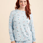 Woman wearing a light blue pajama set with a duck pattern on a beige background