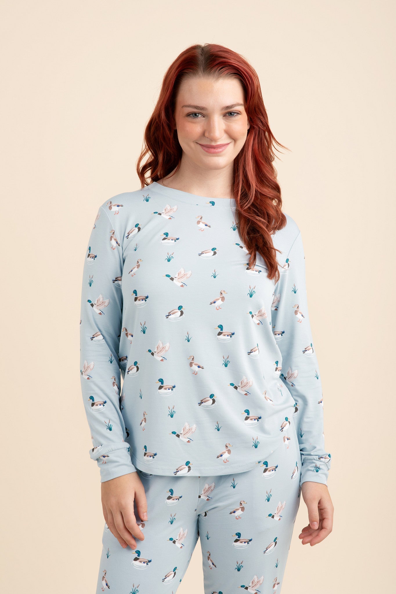 Woman wearing a light blue pajama set with a duck pattern on a beige background