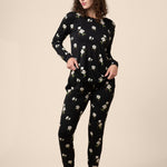 Woman wearing a black floral pajama set on a beige background ::: Model is 5'11" wearing size M ///
