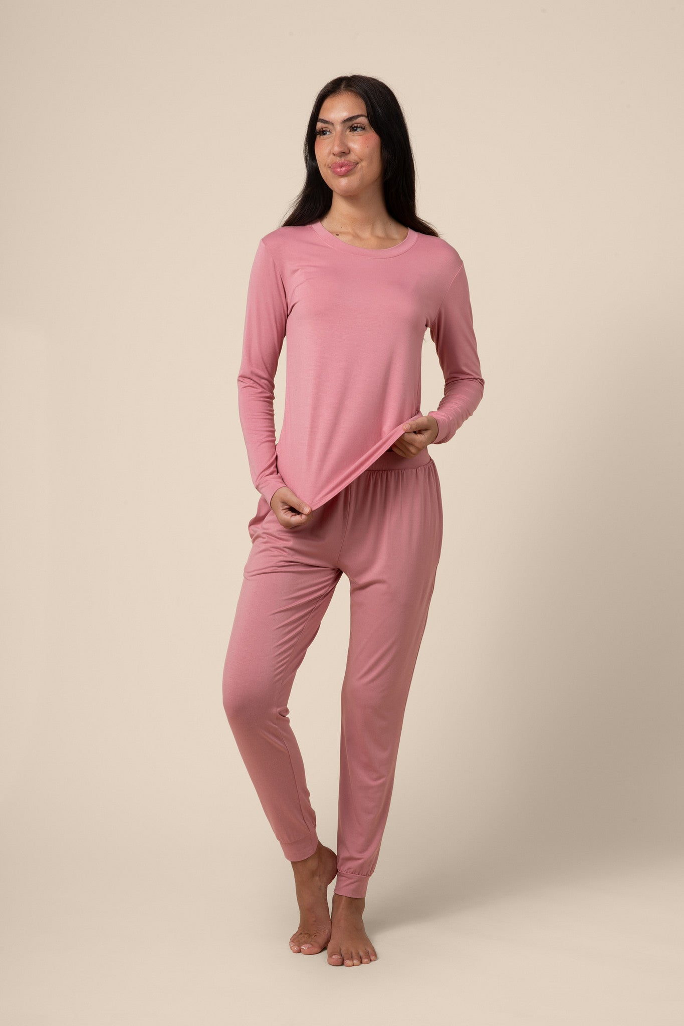 Woman wearing a pink jogger pajama set against a beige background 