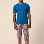 Male model wearing the Men's Lounge Pants in Patriotic Gingham paired with a crew neck in Tahoe while standing in front of a beige background 