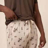 Man showcasing Classic Cowboy patterned pants with drawstring over a brown t-shirt on a beige background