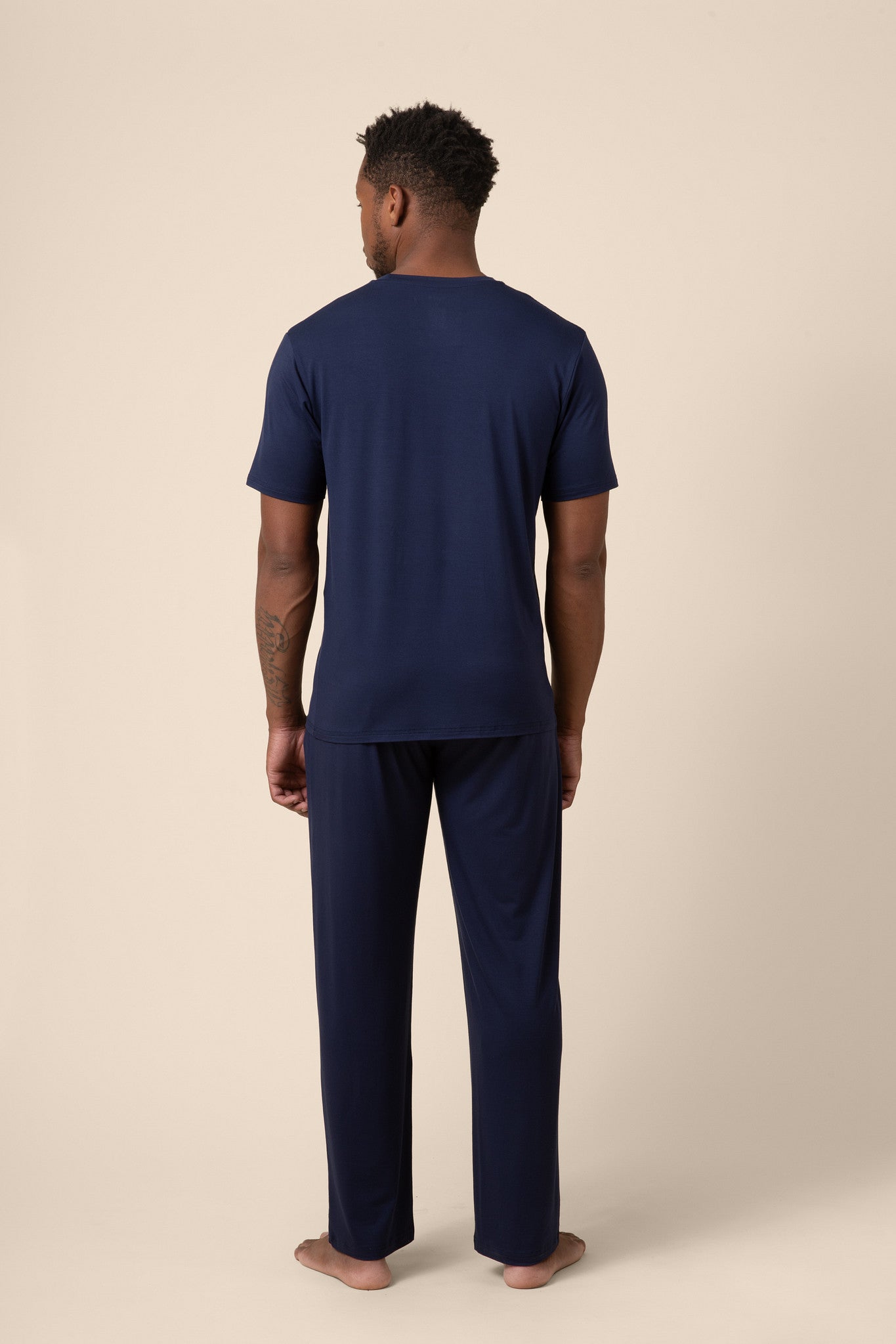 Man showing back side of Men's Short Sleeve & Pant PJ Set in Navy on beige background