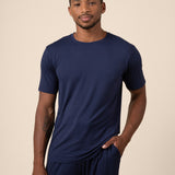Man posing in Men's Short Sleeve & Pant PJ Set with pocket in Navy on beige background