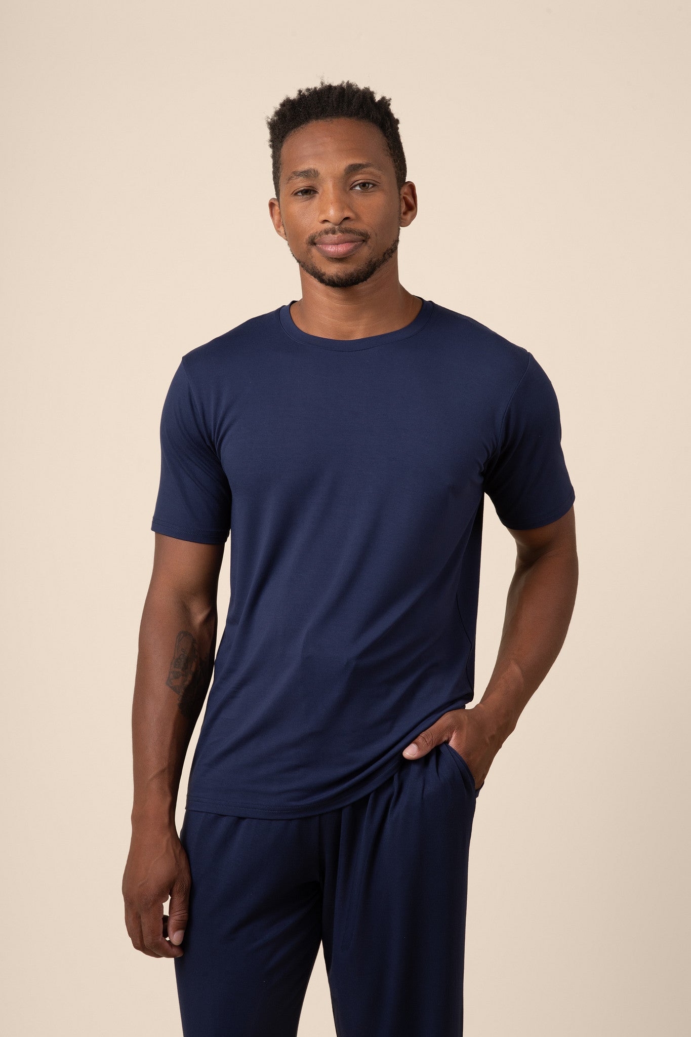 Man posing in Men's Short Sleeve & Pant PJ Set with pocket in Navy on beige background