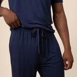 Man showcasing the Men's PJ Pant  with drawstring in Navy over a Men's Navy short sleeve tee on beige background