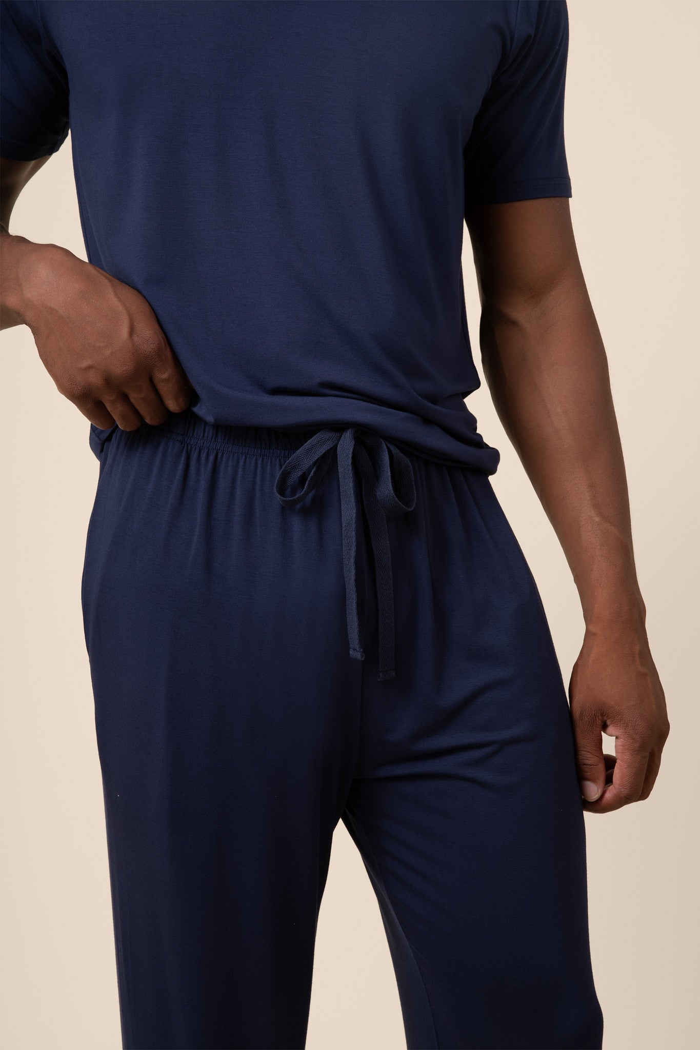Man showcasing the Men's PJ Pant  with drawstring in Navy over a Men's Navy short sleeve tee on beige background