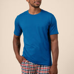 Man wearing blue Men's Short Sleeve t-shirt & Pant PJ Set in Patriotic Gingham print with pocket on a beige background