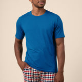 Man wearing blue Men's Short Sleeve t-shirt & Pant PJ Set in Patriotic Gingham print with pocket on a beige background