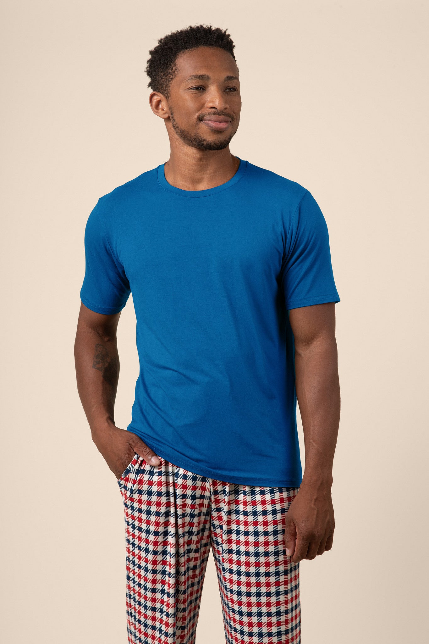 Man wearing blue Men's Short Sleeve t-shirt & Pant PJ Set in Patriotic Gingham print with pocket on a beige background