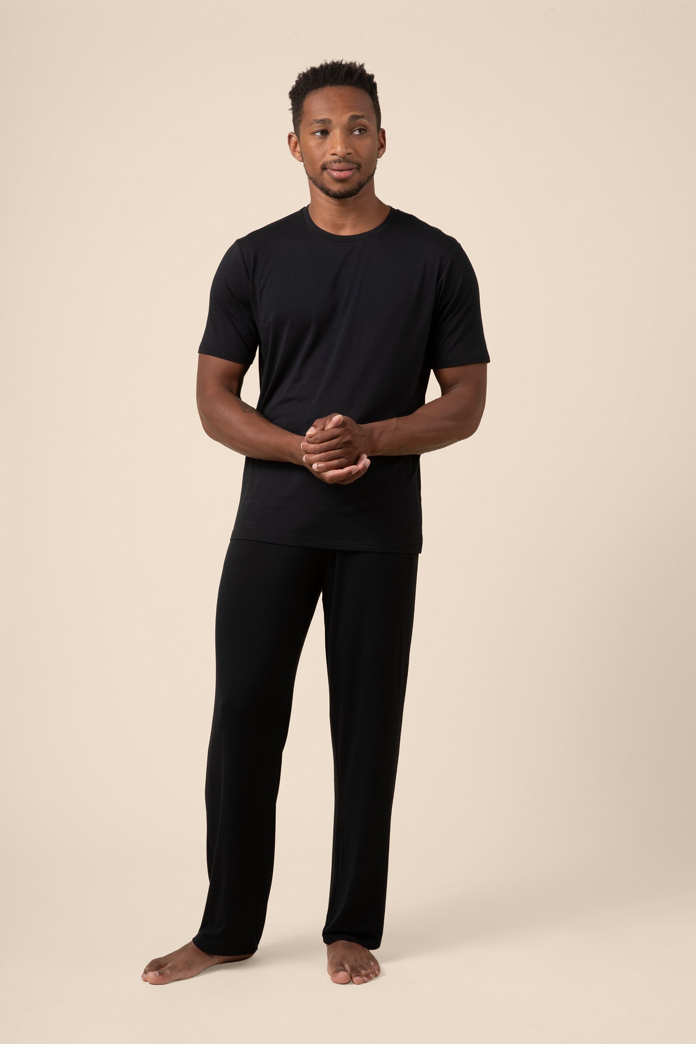 Man wearing Black Men's Short Sleeve & Pant PJ Set on beige background