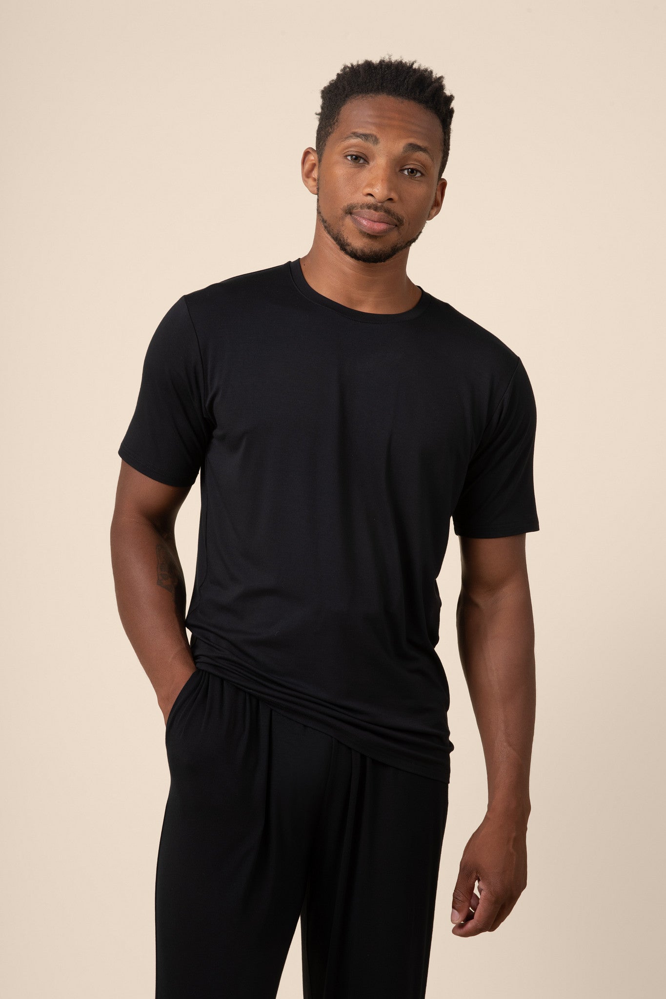 Man posing in Men's Short Sleeve & Pant PJ Set with pocket in midnight on beige background